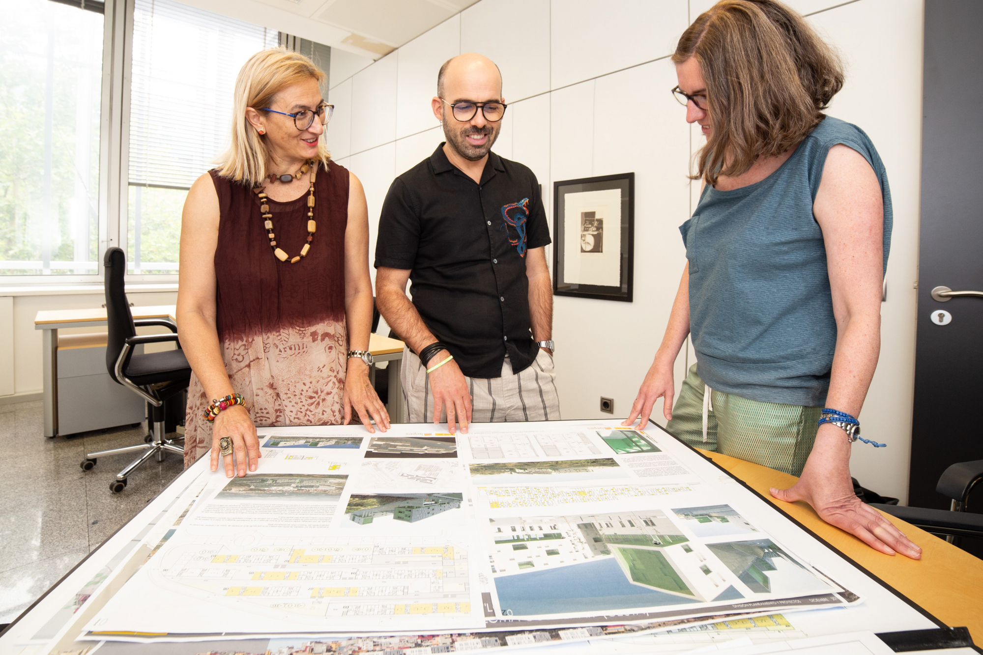 Tres empleados de SEPES en un despacho hablando sobre unos planos
